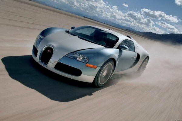 Bugatti Veyron supercar blue and gray in motion on a sandy highway