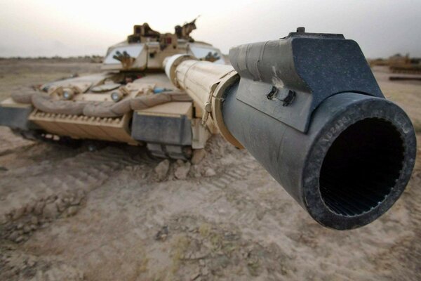 The barrel of the tank s cannon is aimed at the frame against the background of sandy landscapes