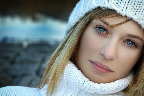 Mädchen mit blauen Augen im weißen Pullover und Hut