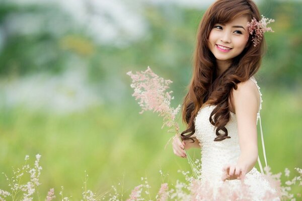 Schöne asiatische Frau im Feld mit einem Blumenstrauß