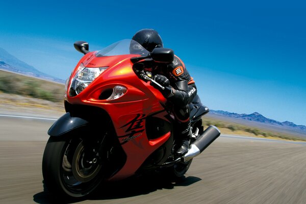 Hombre en una motocicleta roja brillante, paseo en moto de alta velocidad