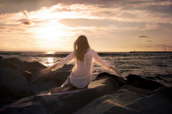 A girl on a rocky beach in a white shirt