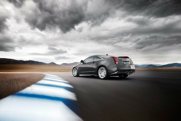 Cadillac en una pista de alta velocidad bajo un cielo gris nublado