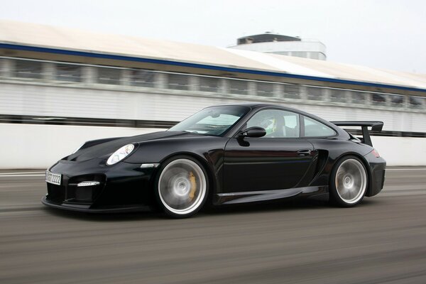 Black Porsche 911 racing on the racetrack