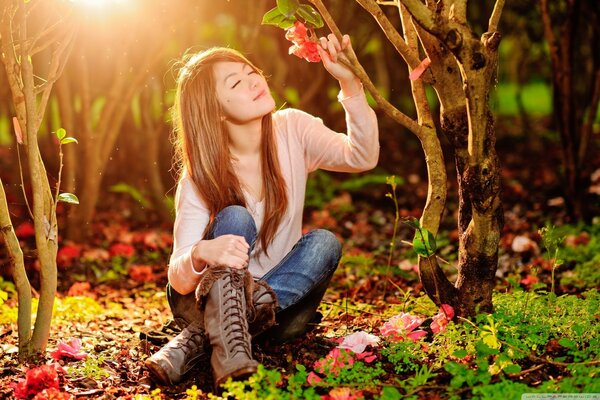 A girl with her eyes closed is sitting on the grass