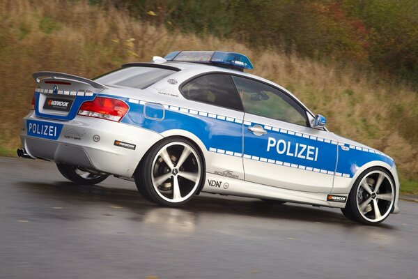 White and blue police car on a wet road