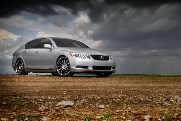 Lexus argent debout dans un terrain rocheux sur fond de ciel nuageux gris