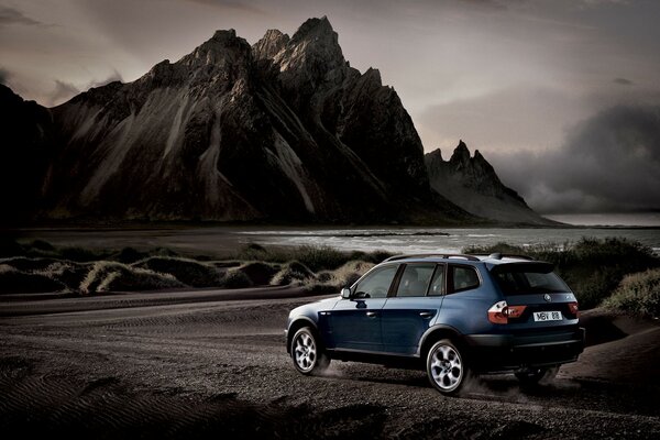 Blue bmw x3 on the background of mountains and water