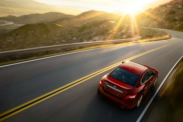 Driving on the road between the hills in a Nissan Maxima