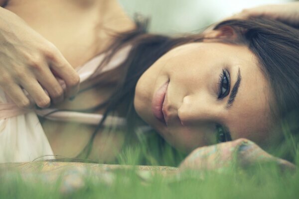 The face of a brunette girl lying on the grass. Macro image