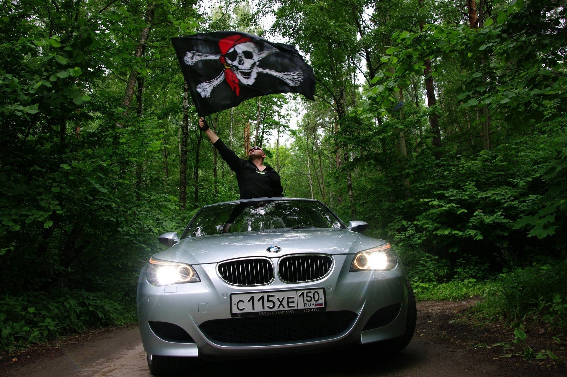 grey colour a man with a flag black flag skull auto bmw greens forest nature lights silver car machine guy flag cars transport vehicle