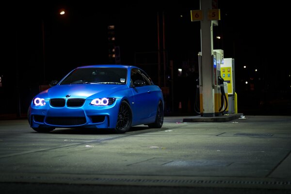 Coche azul por la noche en la gasolinera