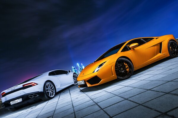 Lamborghini blanco y naranja en el fondo de las luces de la noche de la ciudad de Moscú