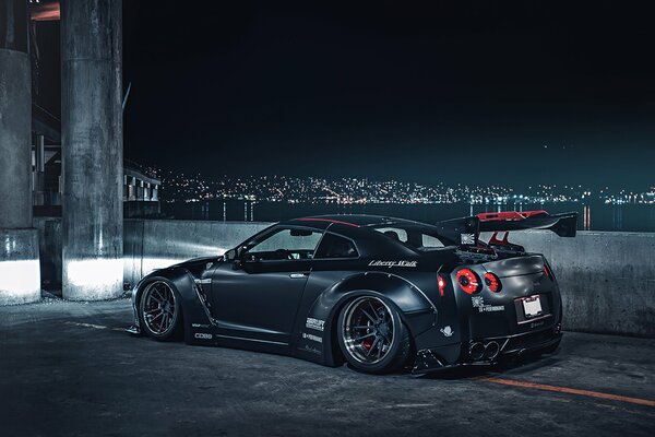 Nissan deportivo gris en el fondo de la ciudad nocturna