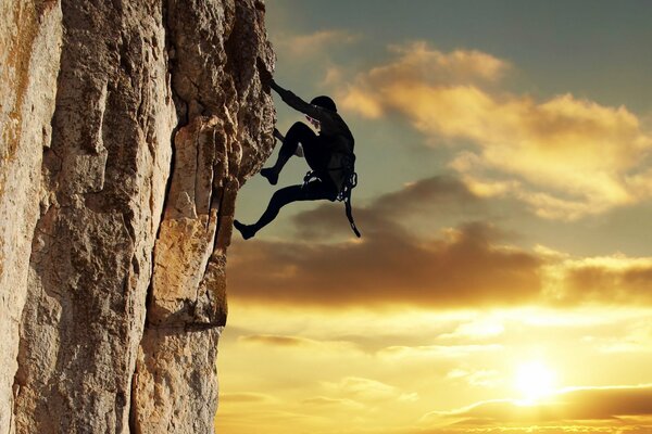 A climber in a black suit climbs a cliff