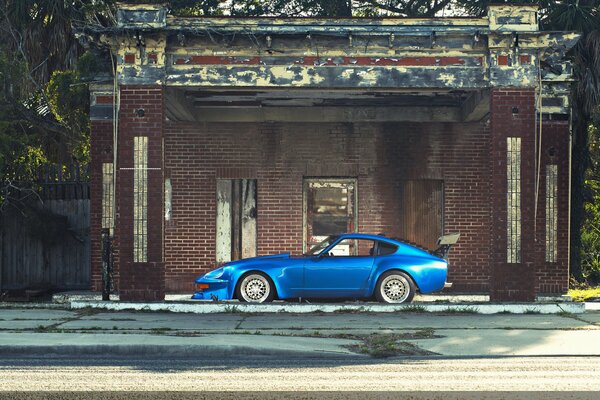 Elegante datsun 240Z azul en el fondo de una casa abandonada