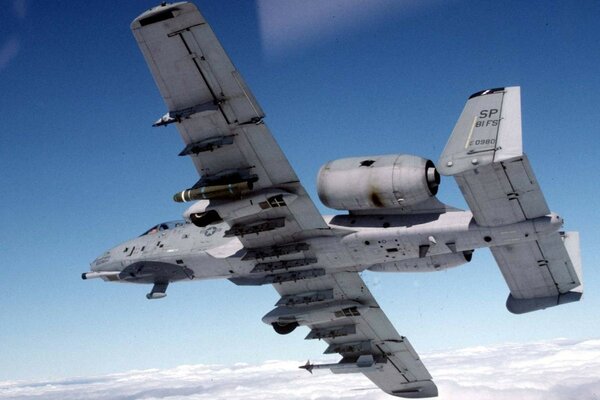 Un avion militaire vole au-dessus des nuages