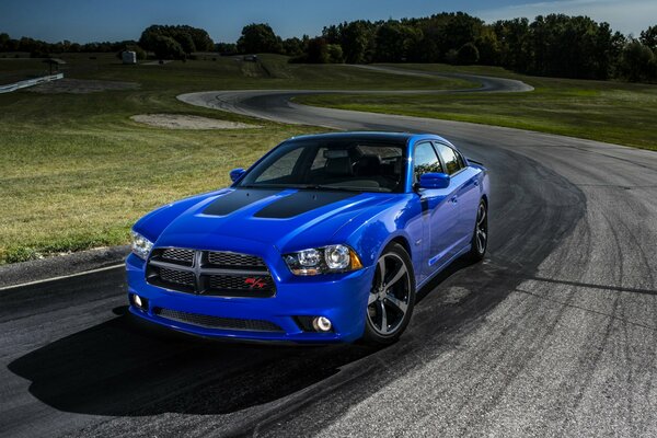 Un Dodge azul vuela por la pista contra el fondo del campo 