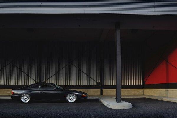 A black car is parked under a canopy