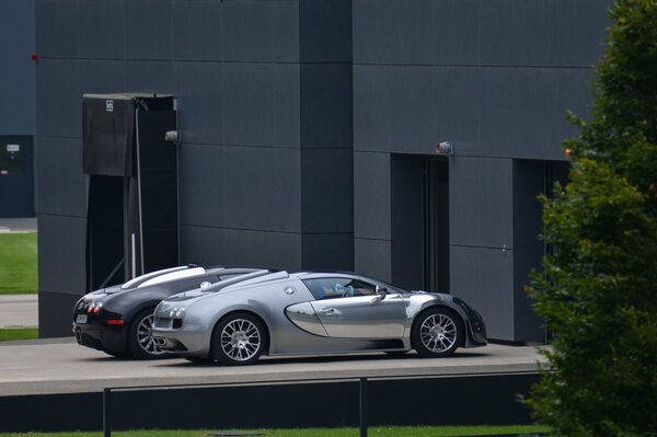 Vicino all edificio grigio ci sono tre auto sportive