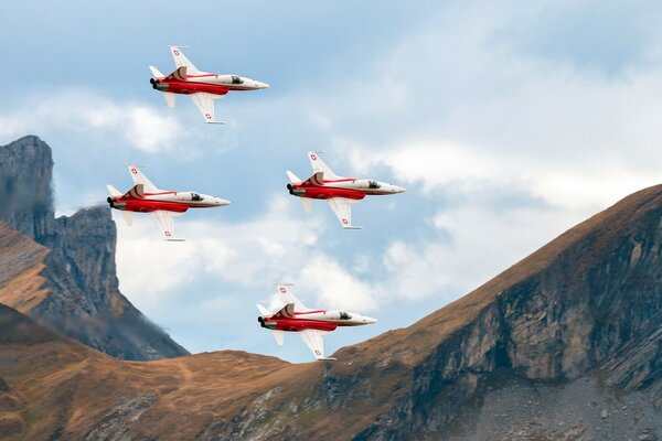 4 aviones rojos y blancos en las montañas