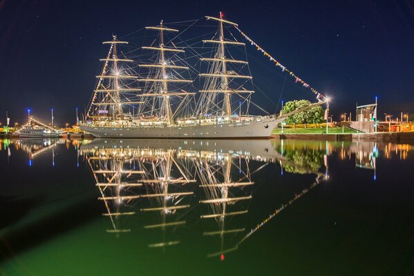 Sailboat on the river with lanterns near the shore