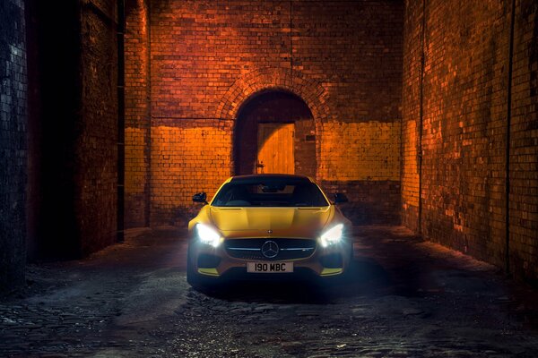 Voiture jaune se dresse sur fond de mur de briques