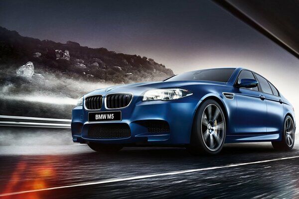 Blue bmv m5 rides on the highway against the background of a mountain