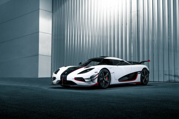 White sports car with red and black inserts on a gray wall background