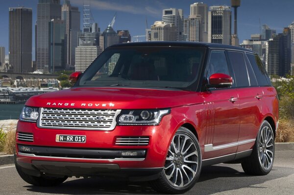 Red Range Rover sta di lato e dietro di essa la città