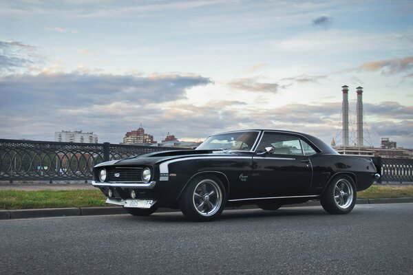 Chevrolet car in black on the background of factory pipes