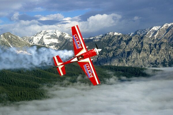 Kleines rotes Flugzeug vor dem Hintergrund der schneebedeckten Berge