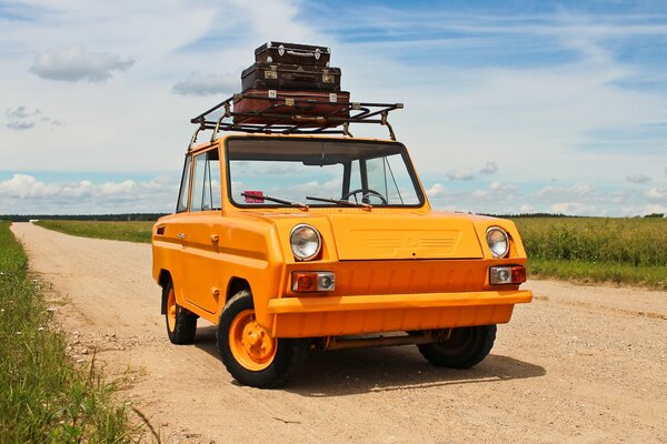 Ungewöhnliches altes, orangefarbenes Auto mit Koffern auf dem Dach