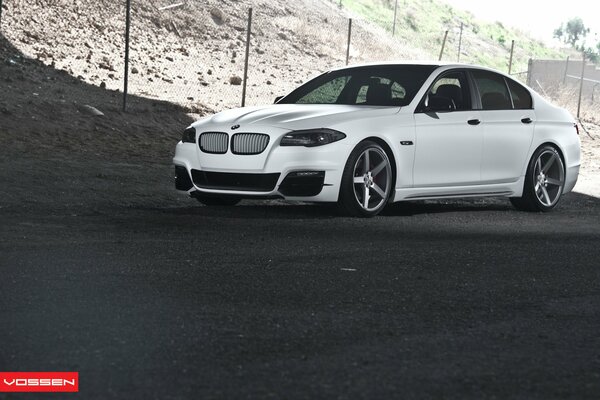 White BMW 5 series vossen on the background of the slope