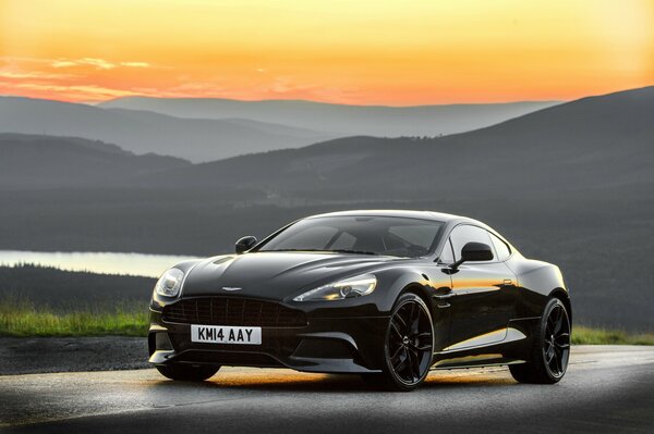 Schwarzer Aston Martin vor dem Hintergrund einer wunderschönen Landschaft