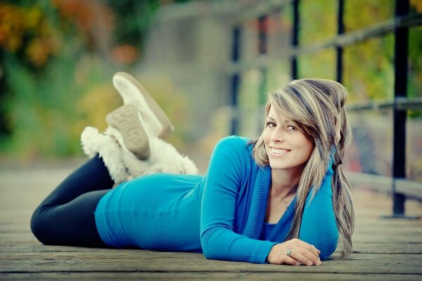 The girl is lying on a wooden bridge