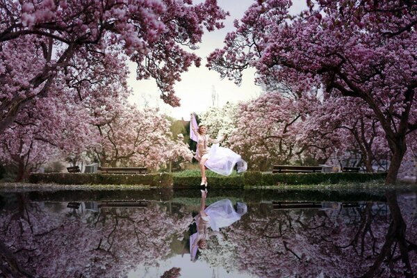 Девушка в парке у озера среди цветущих деревьев