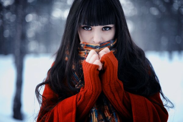 A brunette girl in red mittens stands on a snowy street