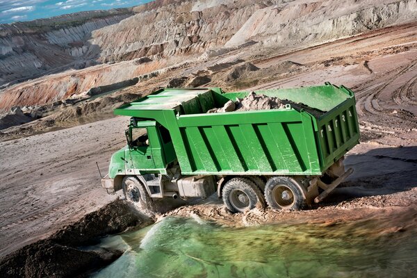 Camion vert avec du sable sur la carrière