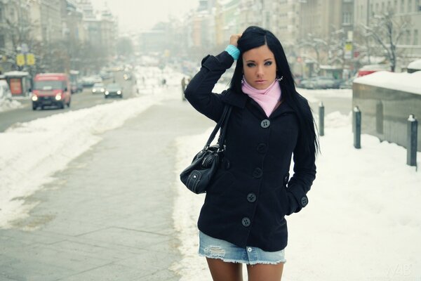 Una ragazza in una gonna corta si trova sullo sfondo di un paesaggio invernale