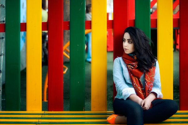 Sad woman on a colored fence background