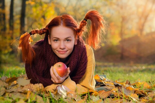 A red-haired girl with an apple in an autumn oesu