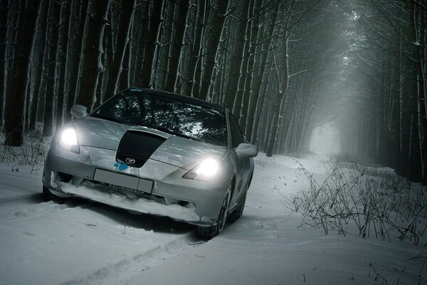 Weißer Toyota auf dem Hintergrund eines verschneiten Waldes