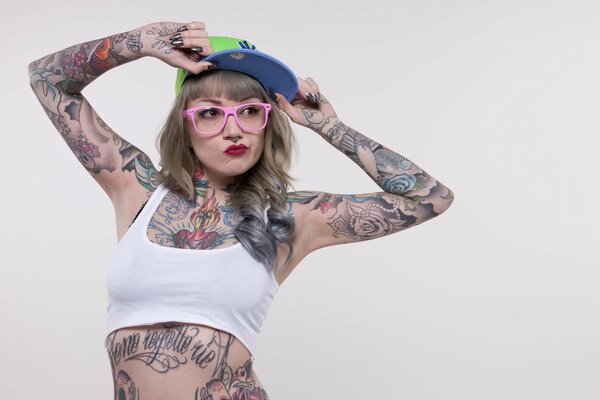 Chica tatuada en camiseta sin mangas y gafas de sol