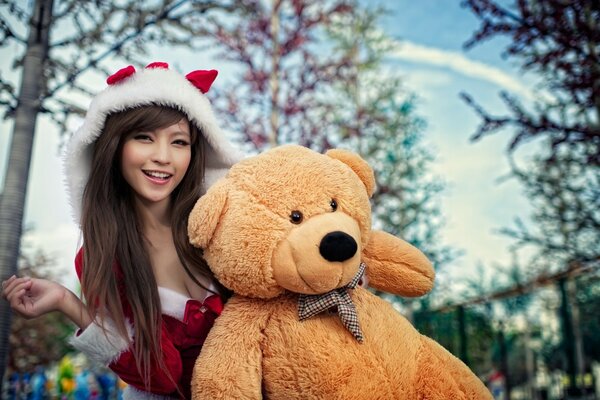 A girl in a Christmas costume with a big bear