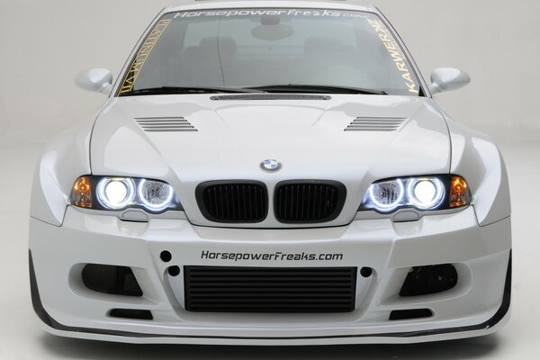 White BMW with headlights on. Front view