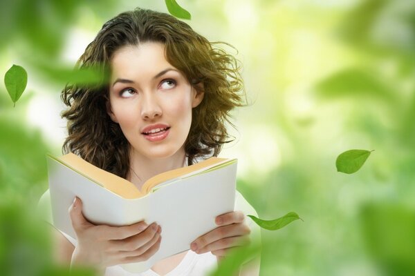 Fille avec un livre sous les feuilles qui tombent