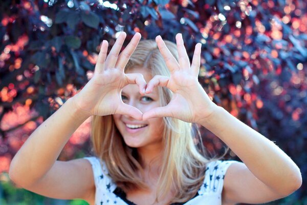 Blonde girl shows her heart with her hands