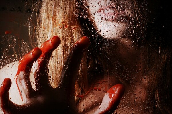 The girl clings to the wet glass with bloody fingers