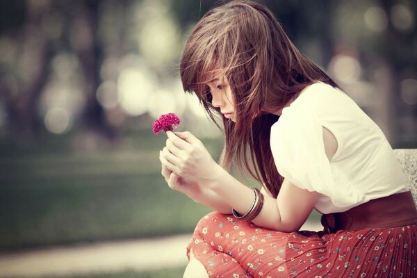 Sad brunette with a flower in her hands